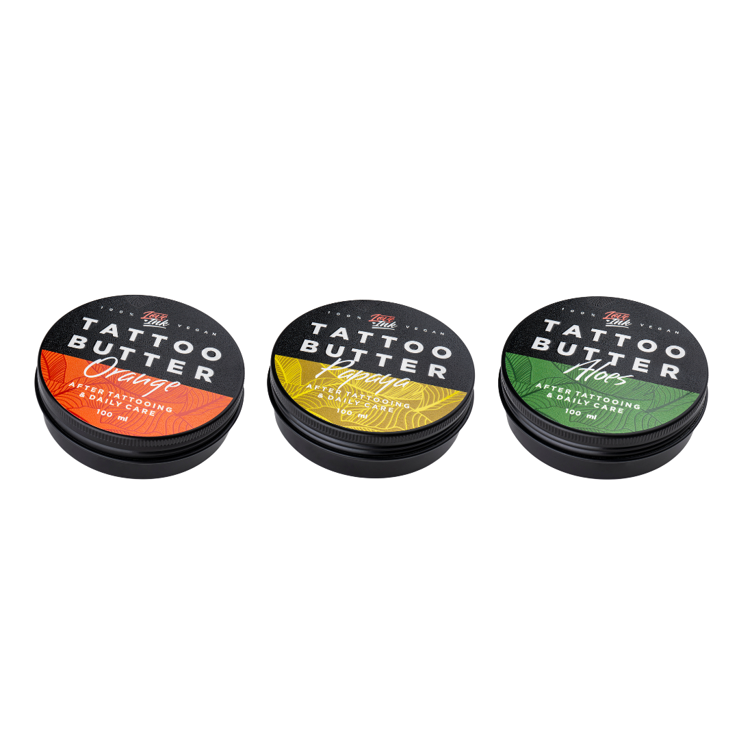 Tři balení Tattoo Butter 100 ml v hliníkových plechovkách - se žlutou etiketou Tattoo Butter Papaya, s oranžovou etiketou Tattoo Butter Orange a se zelenou etiketou Tattoo Butter Aloes.