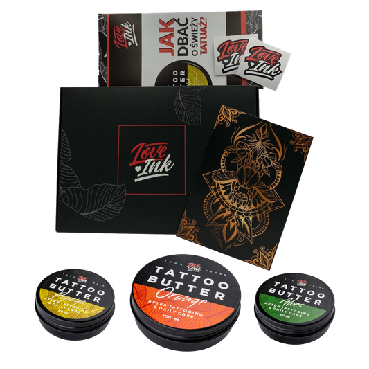 Dárková sada Love Ink Tattoo Butter 100 ml s jasně označenými plechovkami: žlutá plechovka Tattoo Butter Papaya, zelená plechovka Tattoo Butter Aloe a oranžová plechovka Tattoo Butter Orange, uložená v elegantní černé krabičce se zlatými akcenty.