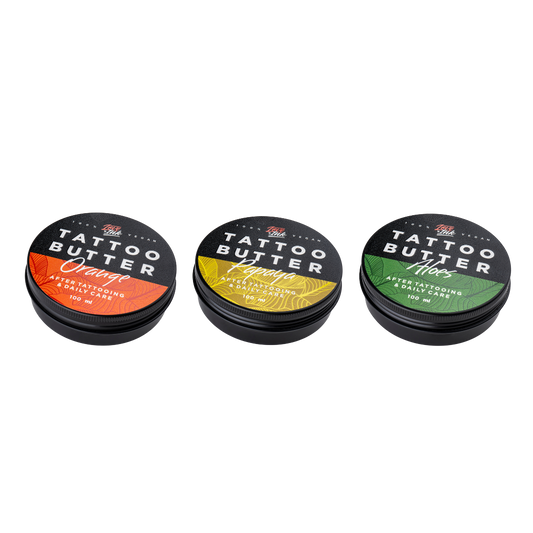 Tři balení Tattoo Butter 100 ml v hliníkových plechovkách - se žlutou etiketou Tattoo Butter Papaya, s oranžovou etiketou Tattoo Butter Orange a se zelenou etiketou Tattoo Butter Aloes.
